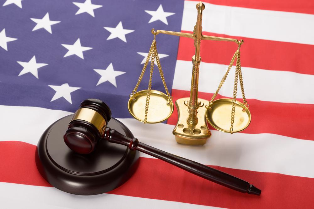 Justice scale and wooden brown gavel on USA flag.